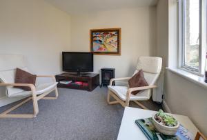uma sala de estar com duas cadeiras e uma televisão em Bridge House By Treetop Property em Cirencester