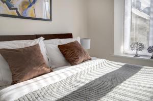 um quarto com uma cama com almofadas e uma janela em Bridge House By Treetop Property em Cirencester