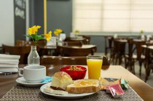 a table with a plate of food and a glass of orange juice at Abudi Hotel in Cuiabá