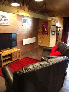 sala de estar con muebles de cuero y TV de pantalla plana en The Lodge en Bedford