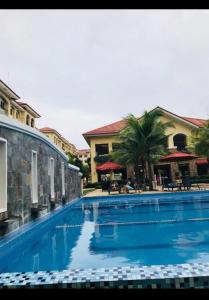 a large blue swimming pool with a building and palm trees at San Remo Oasis SRP Cebu in Cebu City