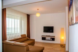 a living room with a couch and a tv on a wall at VELVET RESIDENCE in Mamaia Sat/Năvodari