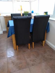 mesa de comedor con sillas negras y mantel azul en Ivydene Cottage en Mablethorpe