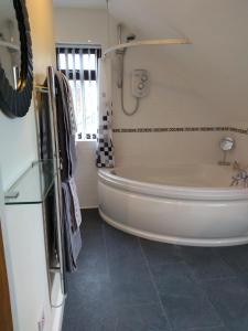 een wit bad in een badkamer met een raam bij Ivydene Cottage in Mablethorpe +6 foto's