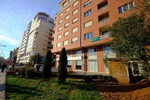 un edificio alto de ladrillo con árboles delante de él en In Center Hotel, en Tirana