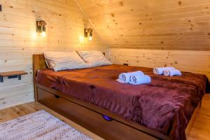 łóżko w drewnianym domku z ręcznikami w obiekcie Happy2cu Cabin w mieście Kolašin