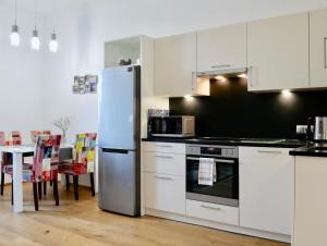 een keuken met een koelkast en een tafel met stoelen bij Suite Mutters in Innsbruck