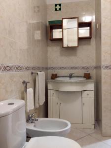 uma casa de banho com um WC branco e um lavatório. em Casa da Gramática em Viana do Castelo