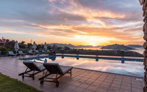 a pool with chairs and a sunset in the background at Aelia & Melitta Villas in Perdhika
