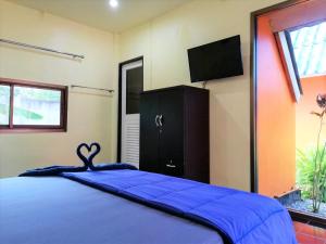 a bedroom with a blue bed and a tv at Phurafa Resort in Phang-nga