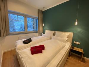 a large white bed with two red pillows on it at Braunlage Lodge in Braunlage