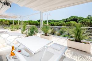 eine Terrasse mit weißen Tischen, Stühlen und Topfpflanzen in der Unterkunft Hotel Palace in Lignano Sabbiadoro