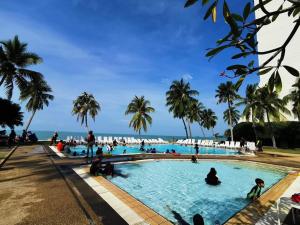 Leute sitzen in einem Pool neben dem Strand in der Unterkunft Tanjung Tuan Regency Port Dickson Pool opened in Port Dickson