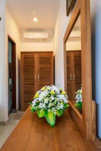a mirror with a bouquet of flowers sitting on a floor at Batik Sekar Bali Guest House in Ubud