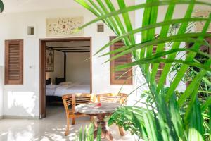 a room with a table and chairs and a bed at Batik Sekar Bali Guest House in Ubud