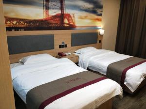 two beds in a hotel room with a painting on the wall at Thank Inn Chain Hotel anhui fuyang funan county department store in Fuyang