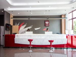 a lobby with a reception counter with red stools at Thank Inn Plus Hotel Jiangsu Suqian Diamond Apartment in Suqian
