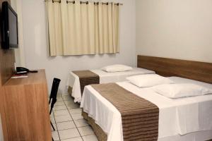 a hotel room with two beds and a desk at Abudi Hotel in Cuiabá