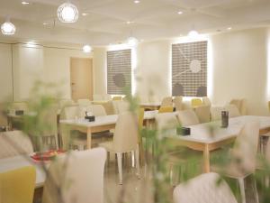 青島市にあるThank Inn Plus Hotel Shandong Qingdao Licang Wan Nianquan Roadの建物内のダイニングルーム(テーブル、椅子付)