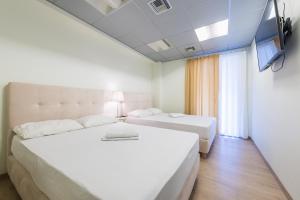 a hotel room with two beds and a flat screen tv at Athens Welcome Suites Apartments in Athens