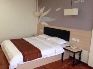 1 dormitorio con 1 cama y 1 mesa con teléfono en Thank Inn Chain Hotel henan luohe liaohe road denis square, en Luohe