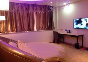 Dormitorio con cama, escritorio y TV en Thank Inn Chain Hotel henan luohe liaohe road denis square, en Luohe