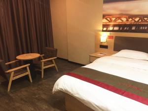 una camera d'albergo con letto, tavolo e sedie di Thank Inn Chain Hotel guangxi liuzhou luzhai county square a Liuzhou
