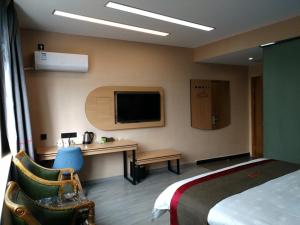 南昌市にあるThank Inn Chain Hotel jiangxi nanchang wanli district zhaoxian roadのベッドと机とテレビがあるホテルの部屋