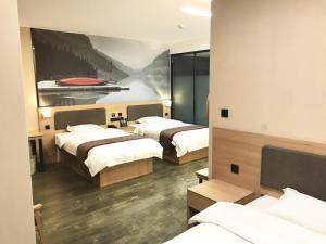 a hotel room with three beds and a painting on the wall at Thank Inn Chain Hotel hebei handan yongnian district development road in Handan