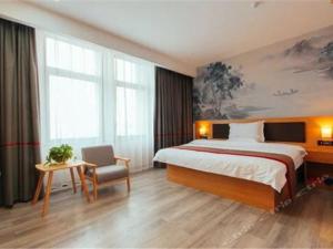 una camera d'albergo con letto e sedia di Thank Inn Chain Hotel henan zhengzhou future road convention and exhibition center a Zhengzhou