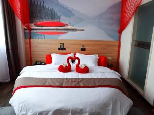 dos cisnes rojos sentados en la parte superior de una cama en Thank Inn Chain Hotel Jiangsu nantong tongzhou district XianFeng Town KaiHao square en Nantong