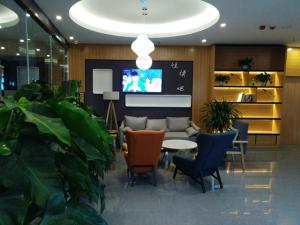 a lobby with chairs and a table and a tv at Thank Inn Chain Hotel Shanxi jinzhong Taigu County xingangwan shopping plaza in Jinzhong