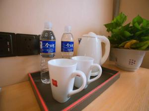 una bandeja con dos tazas y dos botellas de agua en Thank Inn Chain Hotel Shanxi linfen YaoDou zone pingyang north street, en Linfen