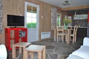 ein Wohnzimmer mit einem TV, einem Tisch und Stühlen in der Unterkunft Le Chalet à Bonnerue in Houffalize