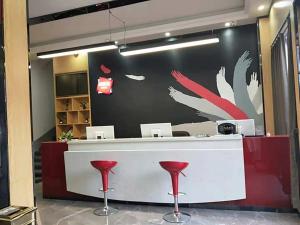 a lobby with a counter with red stools at Thank Inn Chain Hotel anhui fuyang funan county department store in Fuyang