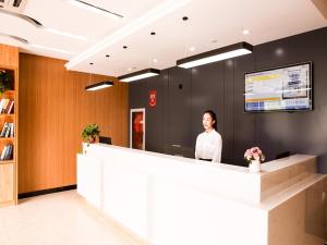 a woman standing behind a counter in an office at Thank Inn Plus Hotel Jiangsu huaian huaiyin area of the Yangtze river east road in Huai'an