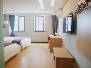 Cette chambre comprend deux lits et une télévision. dans l'établissement Thank Inn Chain Hotel Chongqing nanan district tongjing international store, à Chongqing