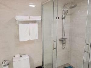 a bathroom with a shower and a toilet and towels at Thank Inn Chain Hotel jiangsu xuzhou jiawang district biantang county in Xuzhou