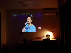 un grand écran avec une femme chantant dans un microphone dans l'établissement Thank Inn Chain Hotel Jiangsu nantong tongzhou district XianFeng Town KaiHao square, à Nantong