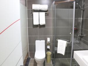 a bathroom with a toilet and a sink and towels at Thank Inn Chain Hotel jiangsu taizhou hailing district yingchun road in Taizhou