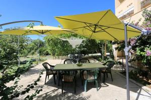 a table and chairs under a yellow umbrella at Little Heaven on Earth - Apartmani Martina in Vlašići
