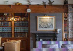 uma biblioteca com lareira, mesa e cadeiras em Bayview Hotel em Ballycotton