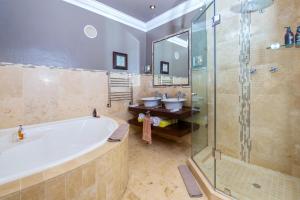 a bathroom with a tub and a shower and two sinks at Alexander Guest House in Knysna
