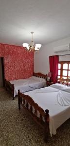 a bedroom with two beds and a red wall at El Campesino Yuri y Nino in Viñales