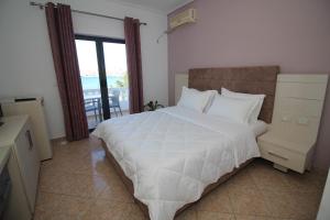 a bedroom with a large white bed and a balcony at Julia Hotel in Sarandë