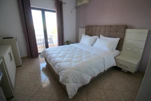 a bedroom with a large white bed and a balcony at Julia Hotel in Sarandë