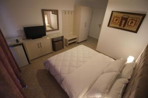 a bedroom with a white bed and a television at Julia Hotel in Sarandë