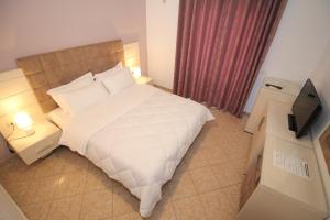 a bedroom with a large bed and a television at Julia Hotel in Sarandë