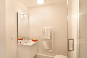 y baño blanco con lavabo y ducha. en Résidence Néméa Clermont Centre en Clermont-Ferrand