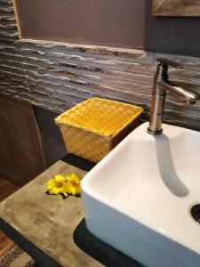 藍海灣的住宿－Coco room，浴室的盥洗盆,在台面上摆放着黄色的花卉